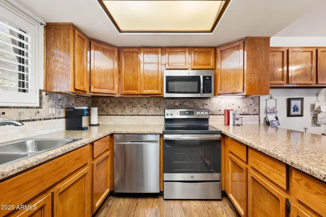 a kitchen with stainless steel appliances granite countertop a refrigerator a sink dishwasher a stove and a refrigerator with wooden floor