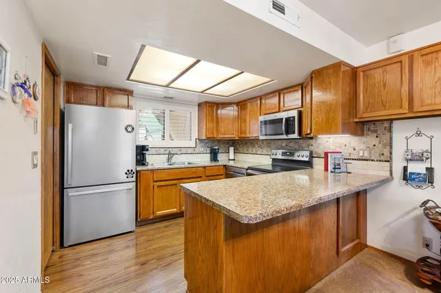 a kitchen with stainless steel appliances granite countertop a stove top oven a sink dishwasher a dining table and chairs with wooden floor