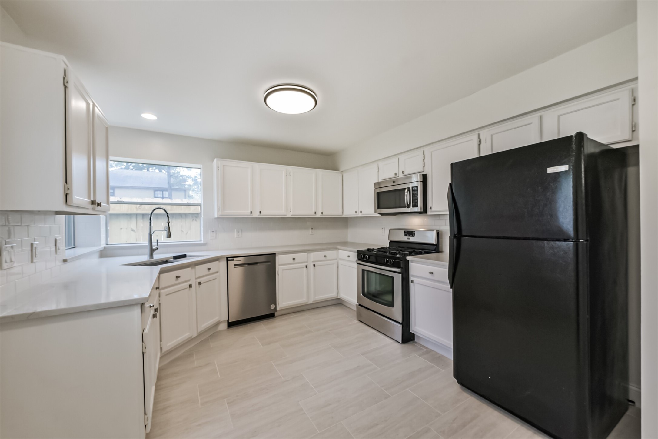 9202 Bayou Bluff Drive Spring, TX 77379 - Photo 11 of 33 This kitchen features quartz countertops, stainless steel appliances, sleek backsplash, and white cabinets.