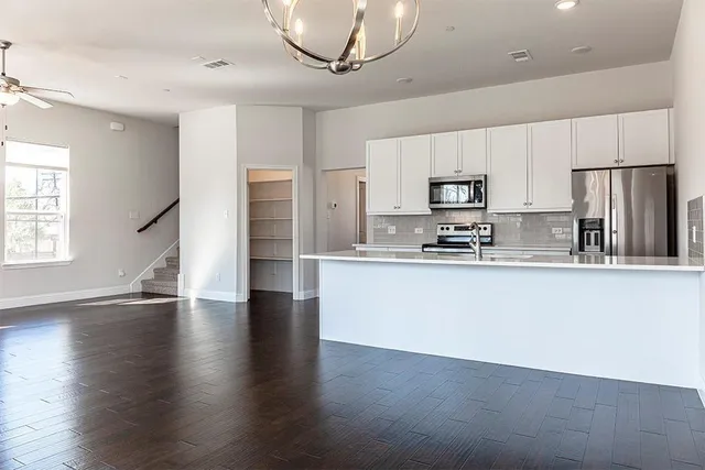 a kitchen with stainless steel appliances granite countertop a refrigerator a stove top oven a sink and dishwasher with wooden floor