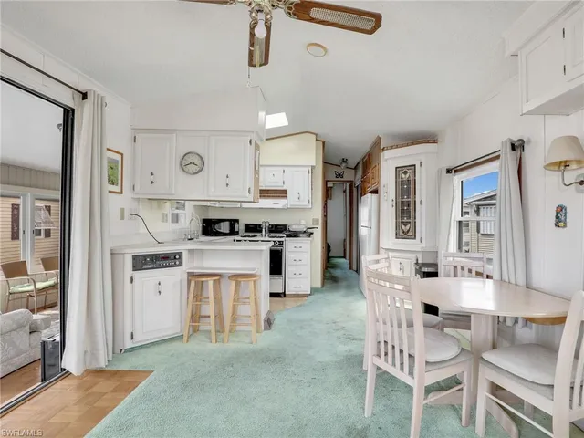 a kitchen with stainless steel appliances kitchen island granite countertop a stove a sink dishwasher and white cabinets with wooden floor