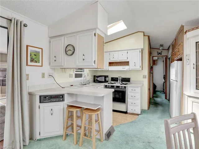 a kitchen with stainless steel appliances granite countertop a stove top oven a refrigerator a sink and dishwasher with white cabinets