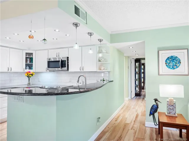 a kitchen with stainless steel appliances granite countertop a sink and white cabinets with wooden floor