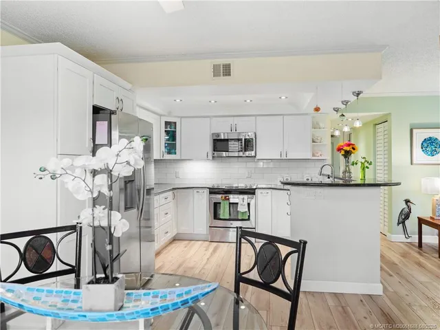 a kitchen with stainless steel appliances granite countertop a kitchen island a stove a table and chairs in it