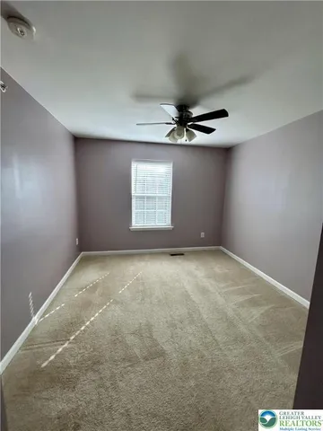 an empty room with a ceiling fan and window