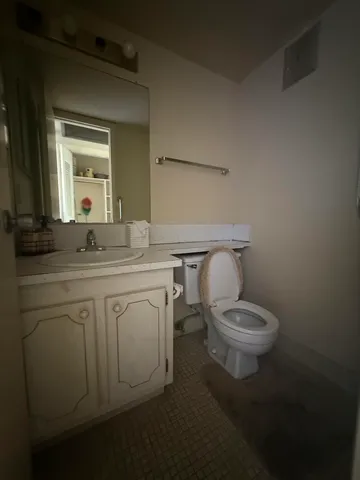 a bathroom with a granite countertop toilet sink and mirror