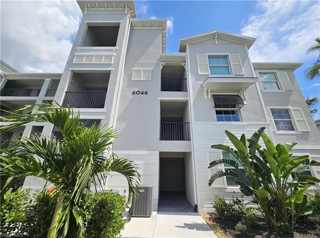 a living room with furniture flowers and wooden floor