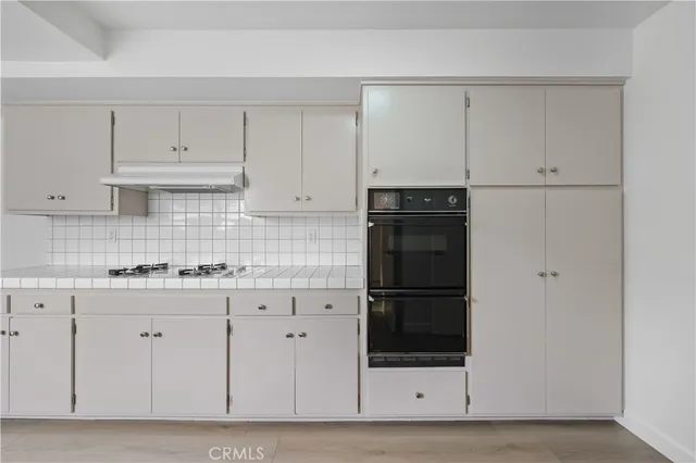 a kitchen with white cabinets and refrigerator