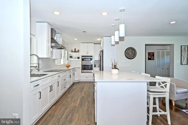 a open kitchen with kitchen island a stove a sink a dining table and chairs