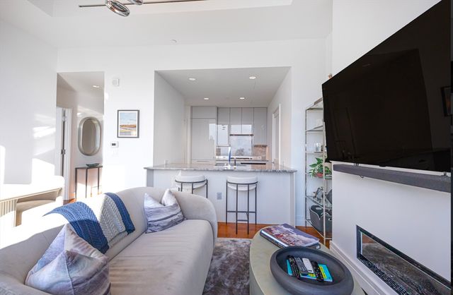 a living room with furniture a flat screen tv and kitchen view