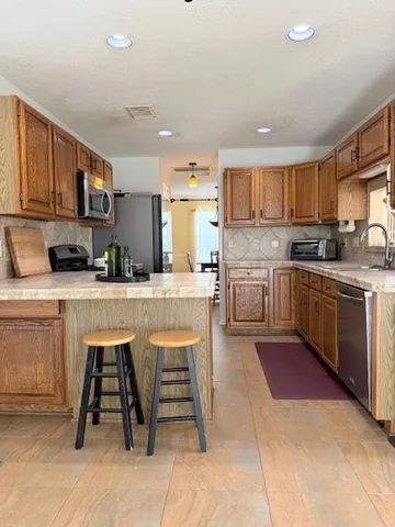 a kitchen with stainless steel appliances granite countertop a table chairs sink and cabinets