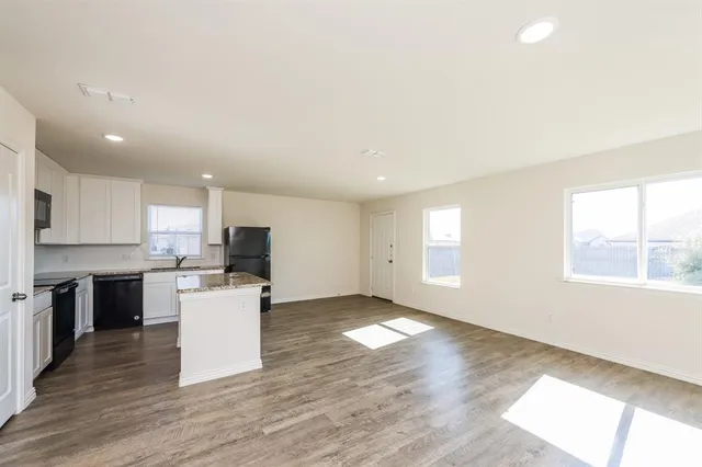 a view of kitchen with microwave a stove a sink dishwasher and a refrigerator with wooden floor