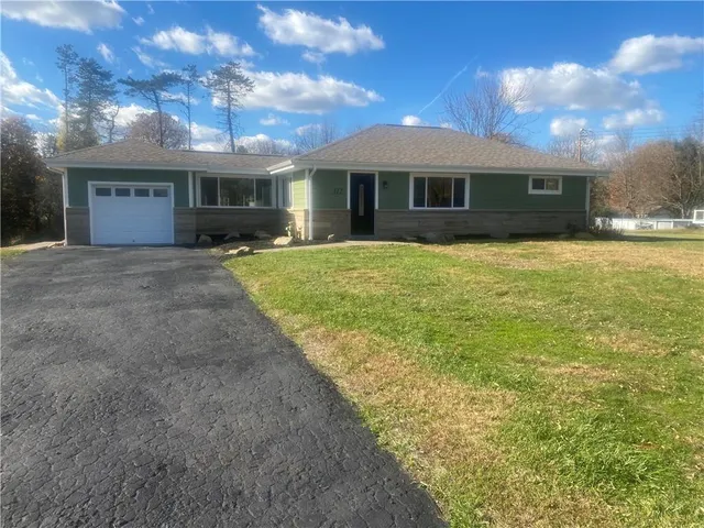 a view of a house with a yard and a large tree