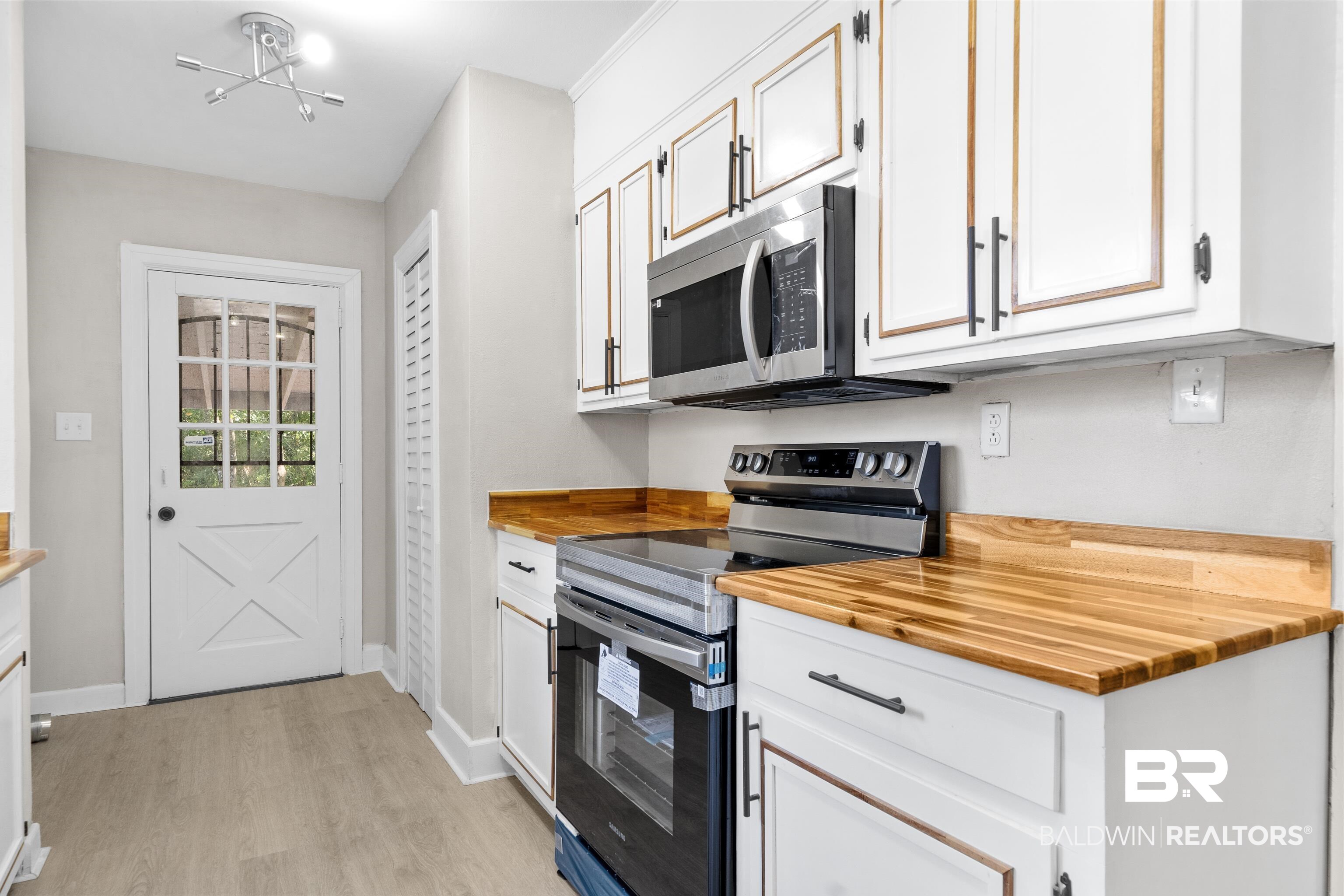 611 Morgan Avenue Mobile, AL 36606 - Photo 15 of 24 Kitchen with white cabinetry, light hardwood / wood-style floors, appliances with stainless steel finishes, and an inviting chandelier