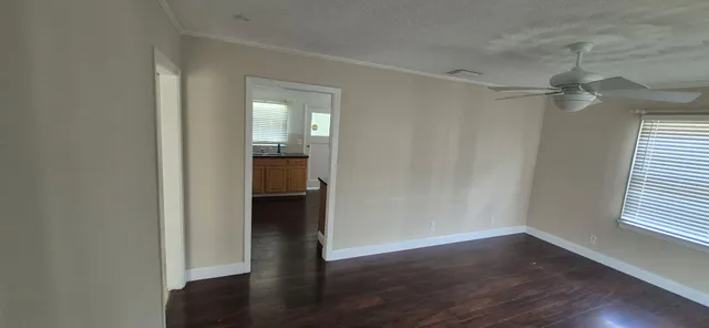 an empty room with wooden floor closet and windows