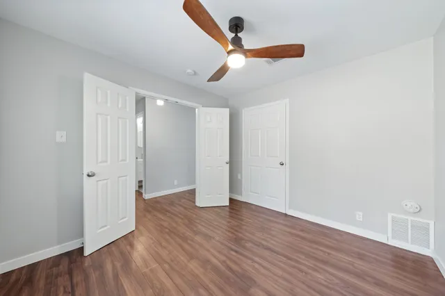 an empty room with wooden floor ceiling fan and windows