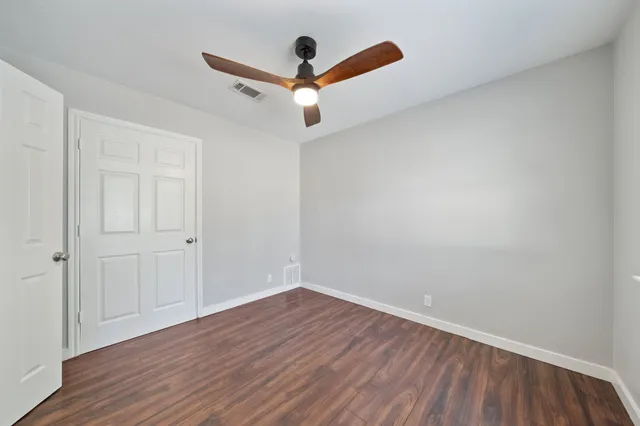 a view of a room with wooden floor and a ceiling fan