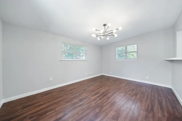 a view of an empty room with a window and wooden floor