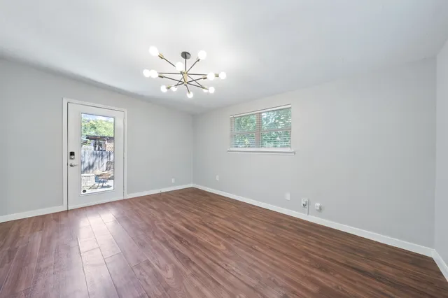 an empty room with wooden floor chandelier fan and windows