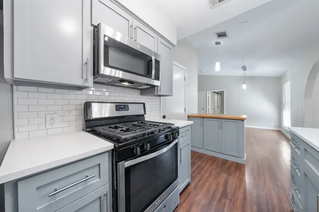 a kitchen with stainless steel appliances a white stove top oven a sink dishwasher and microwave with wooden floor