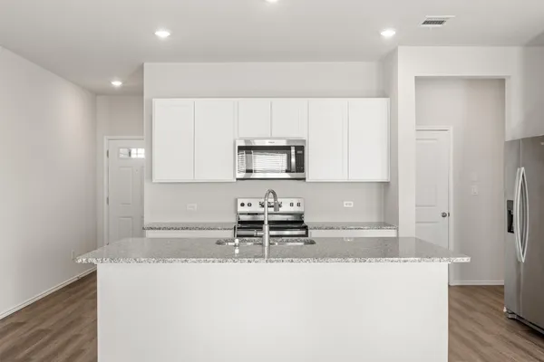 a kitchen with kitchen island granite countertop a stove a sink and a refrigerator