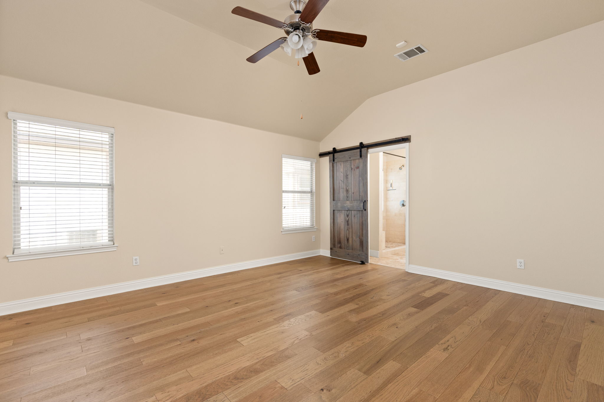 784 Sampson Kyle, TX 78640 - Photo 13 of 40 Rich hardwood floors and vaulted ceilings frame this bedroom opening to an adjacent bath.