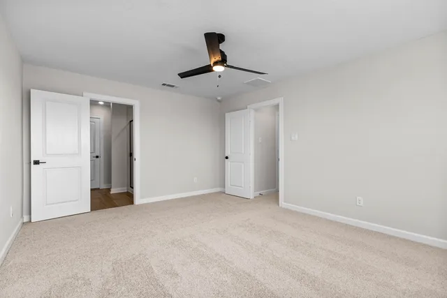a view of an empty room and chandelier fan