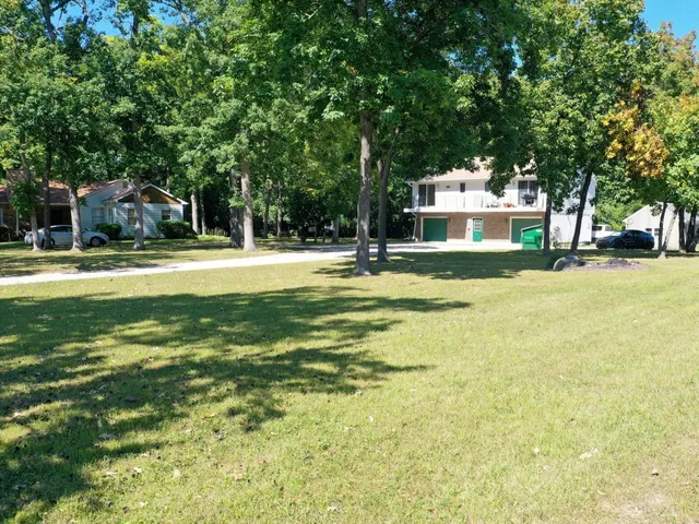 a view of a house with a big yard and large trees