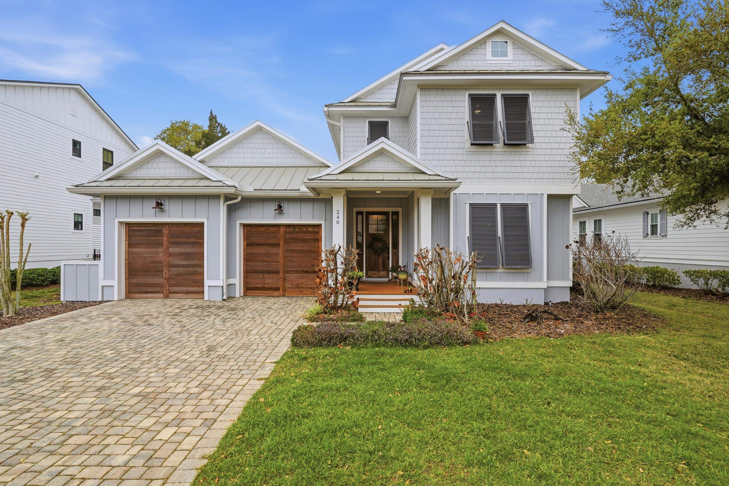 View of front of house featuring board and batten siding, decorative driveway, a standing seam roof, a front yard, and an attached garage