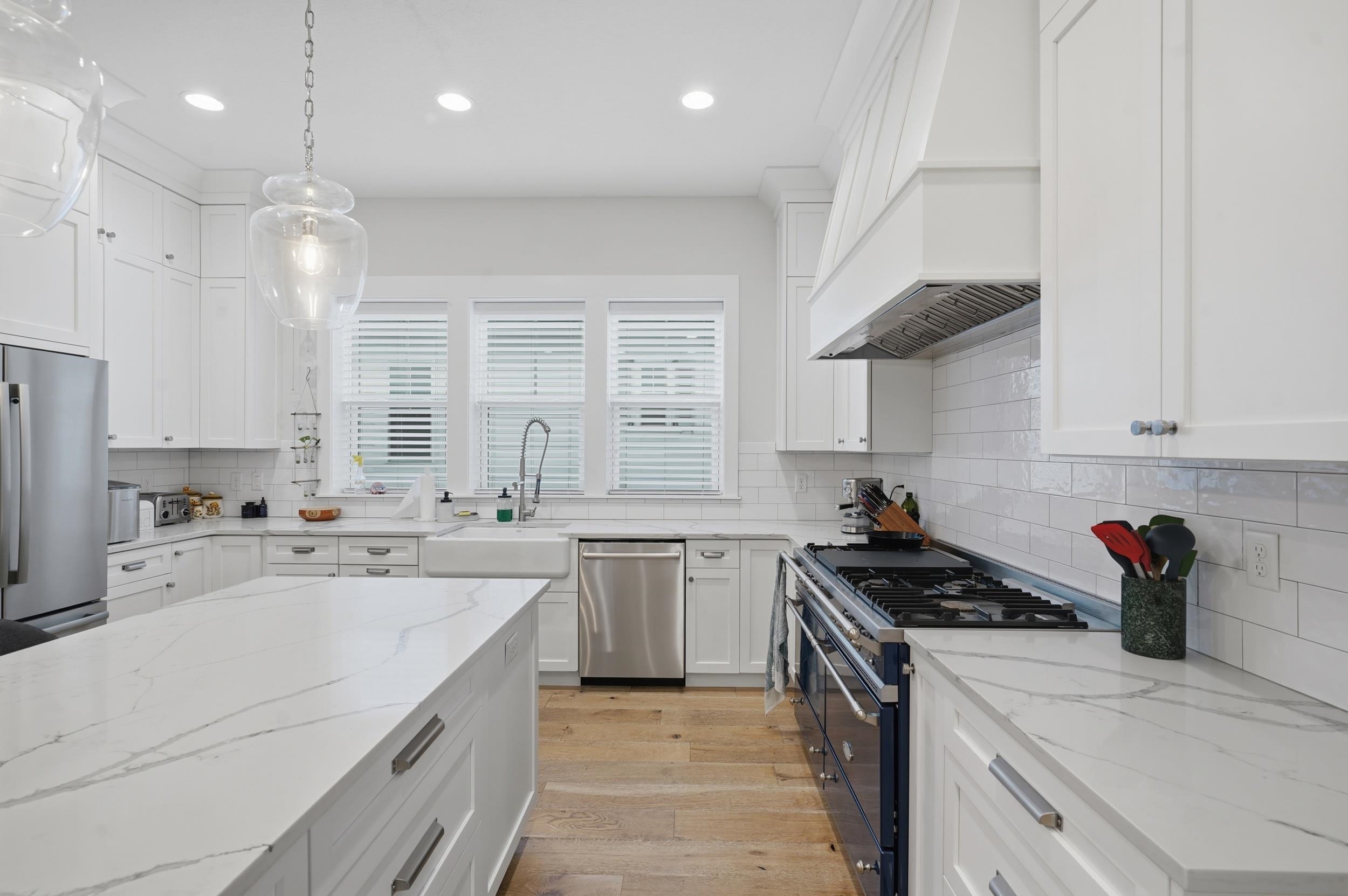 240 Ridgeway Road St. Augustine, FL 32080 - Photo 18 of 38 Kitchen with stainless steel appliances, light wood-type flooring, white cabinetry, light stone countertops, and hanging light fixtures
