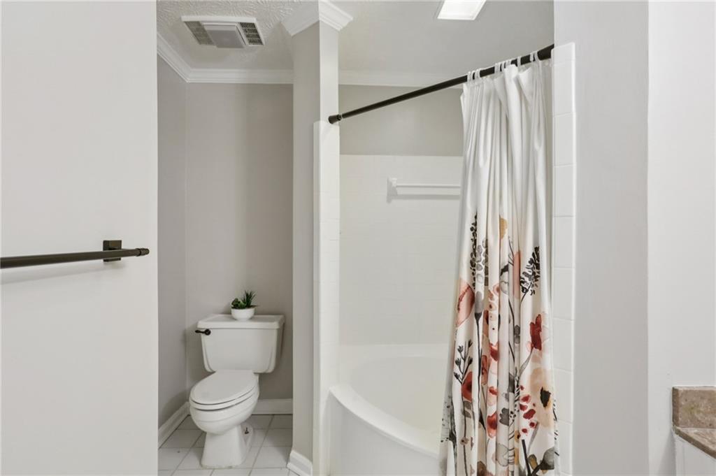 970 Sidney Marcus Boulevard Northeast, Unit 2115 Atlanta, GA 30324 - Photo 14 of 21 a bathroom with a toilet and a shower curtain