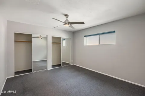an empty room with closet and a ceiling fan