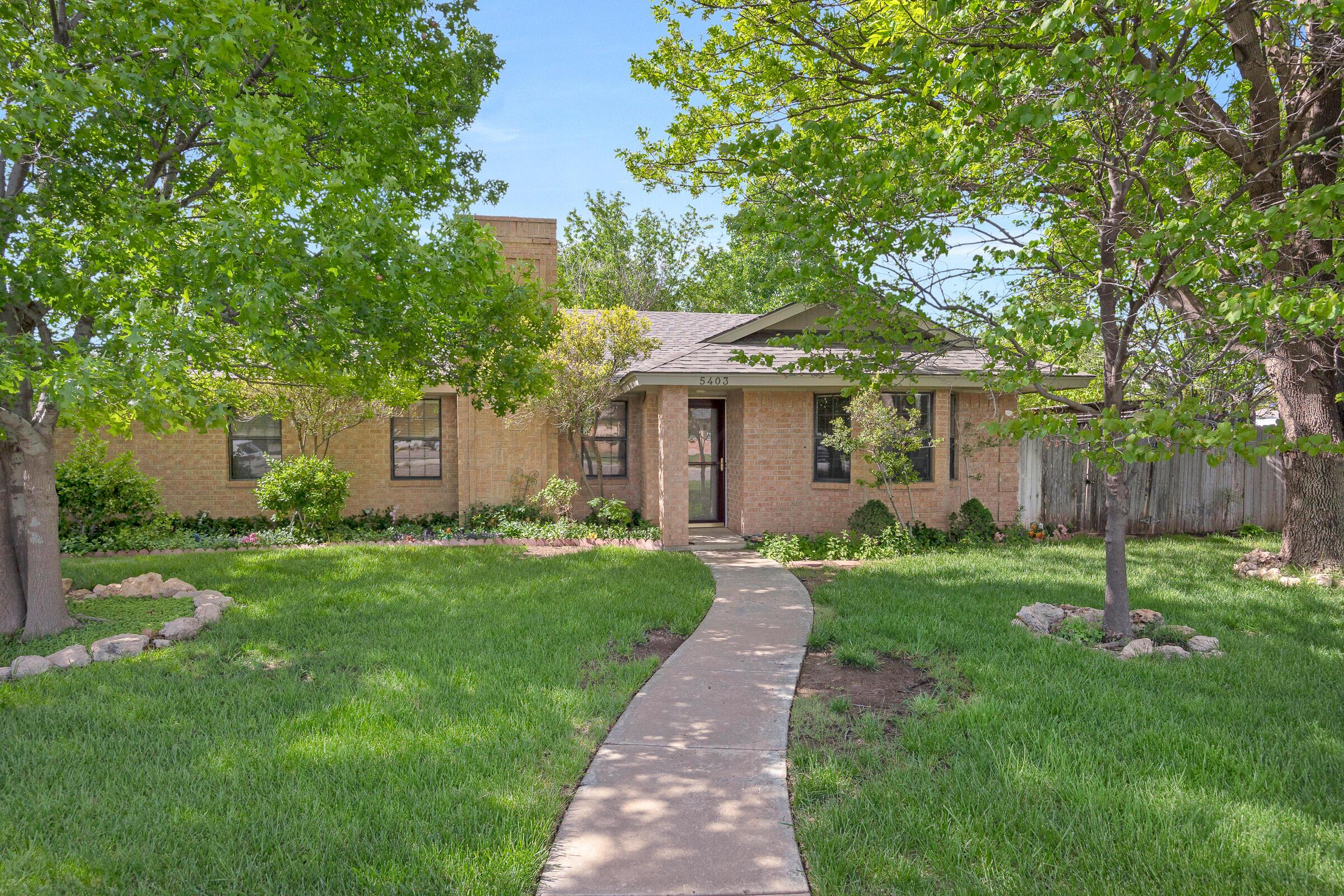 a front view of a house with a yard and trees