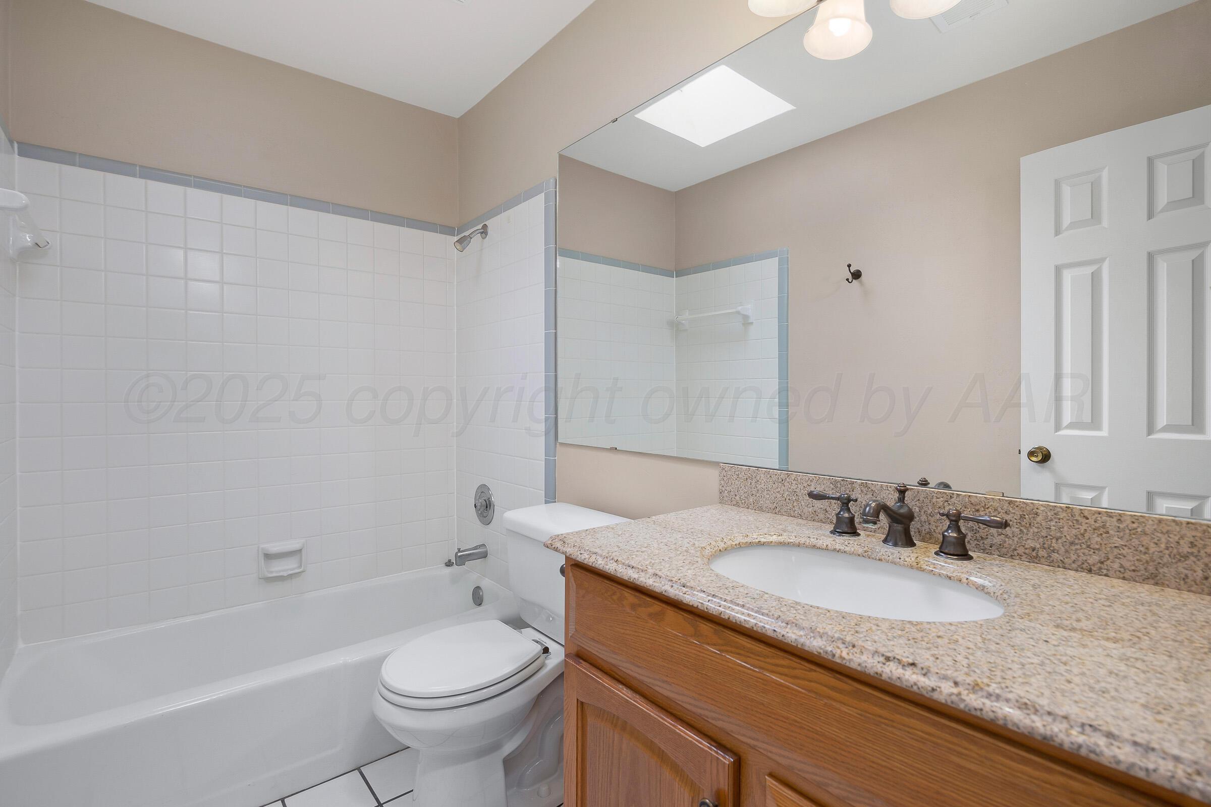 5403 Camp Lane Amarillo, TX 79110 - Photo 18 of 25 a bathroom with a granite countertop sink a toilet a mirror a bathtub and shower
