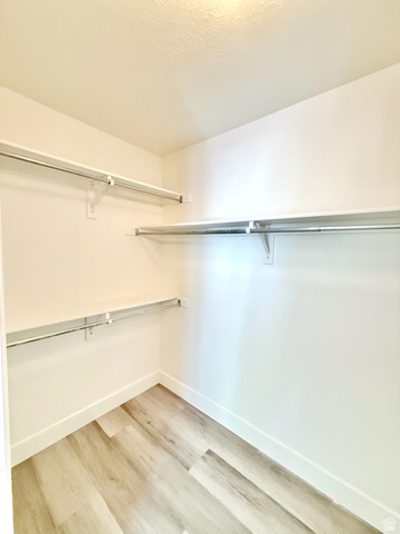 1705 80 East Tooele, UT 84074 - Photo 10 of 22 Walk-in closet featuring light wood-finish flooring, white baseboards, and multiple chrome hanging rods with shelving