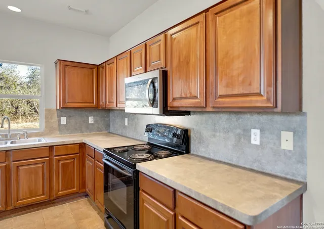 a kitchen with stainless steel appliances granite countertop wooden cabinets a sink and dishwasher a stove with wooden floor