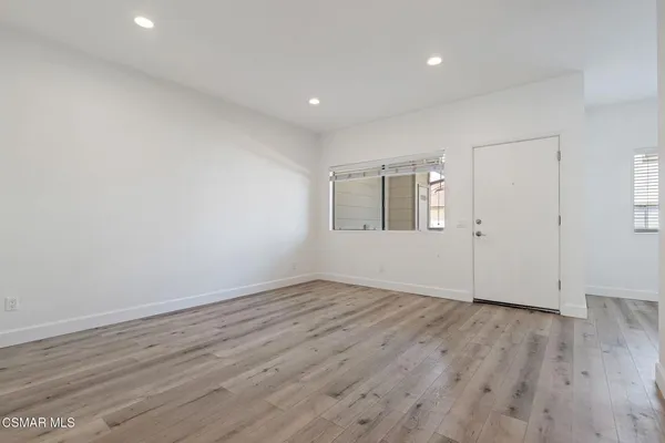 a view of an empty room with wooden floor and a window