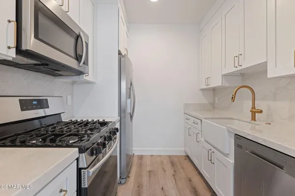 a kitchen with stainless steel appliances a stove a sink and a microwave