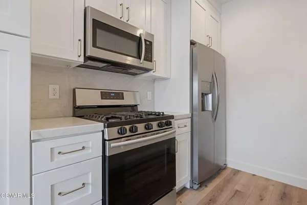 a kitchen with stainless steel appliances white cabinets and stove top oven
