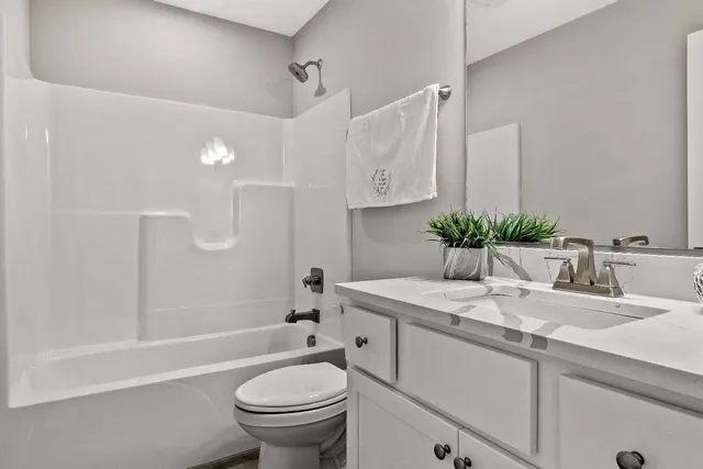 a bathroom with a granite countertop sink mirror vanity and toilet