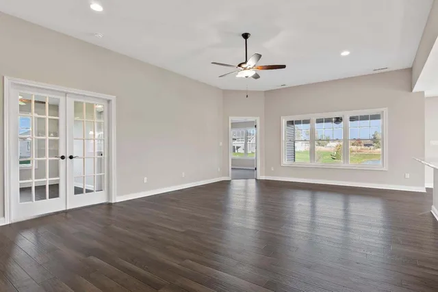 a view of an empty room with a window and wooden floor