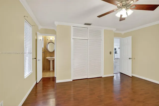 an empty room with wooden floor and ceiling fan
