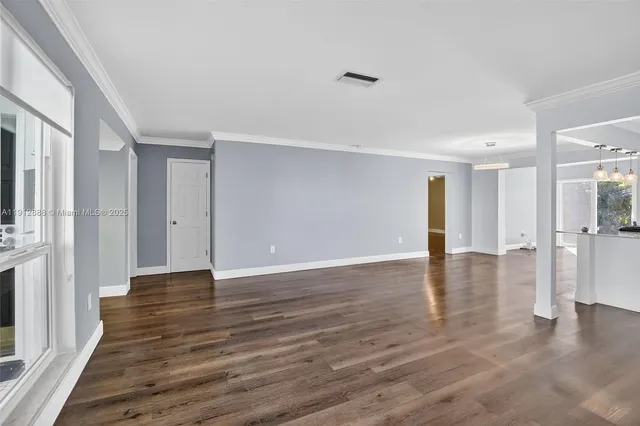 a view of an empty room with wooden floor and a window