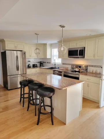 a kitchen with stainless steel appliances granite countertop a stove a sink dishwasher a refrigerator and a microwave with wooden floor