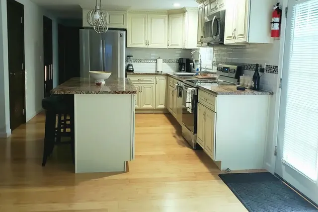 a kitchen with stainless steel appliances granite countertop a refrigerator a stove and a sink