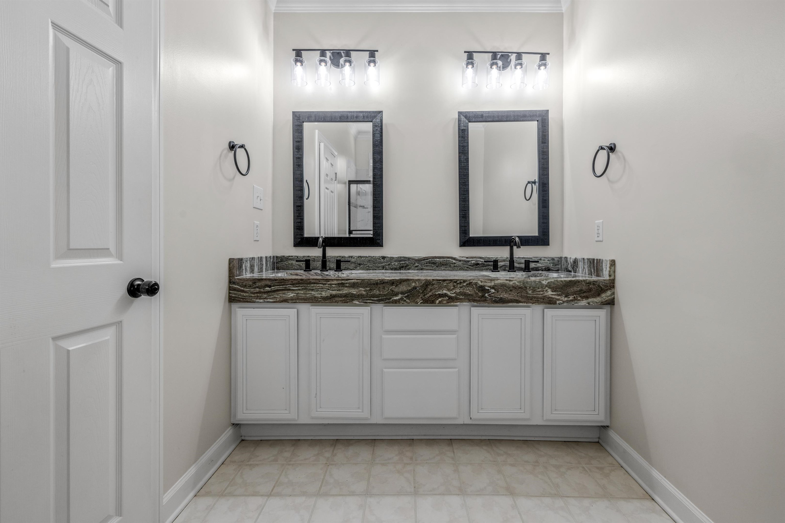 921 Harbor View Drive Memphis, TN 38103 - Photo 29 of 33 Dual vanity with a patterned countertop, individual framed mirrors, and modern matte black fixtures