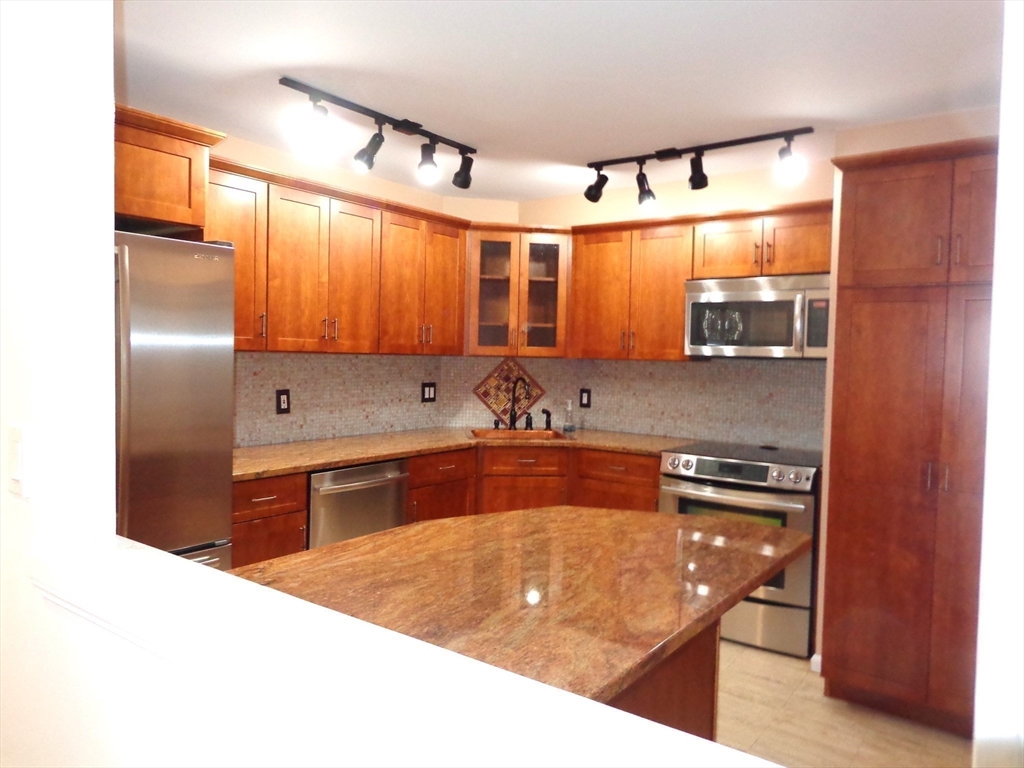 151 Coolidge Avenue, Unit 613 Watertown, MA 02472 - Photo 5 of 16 a kitchen with stainless steel appliances granite countertop a sink stove and refrigerator