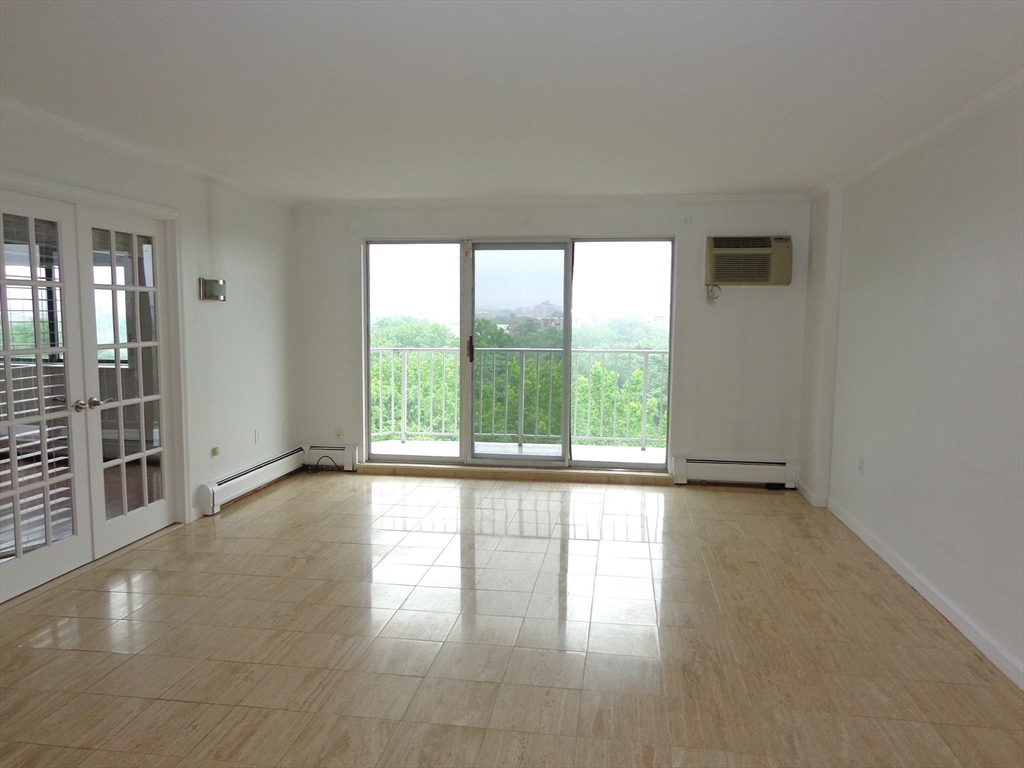 151 Coolidge Avenue, Unit 613 Watertown, MA 02472 - Photo 6 of 16 a view of an empty room with wooden floor and a window