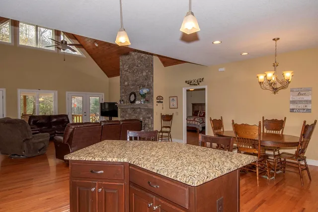 a open kitchen with stainless steel appliances granite countertop a stove kitchen island a dining table and chairs with wooden floor