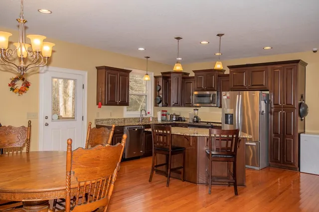 a kitchen with stainless steel appliances a table chairs refrigerator and sink